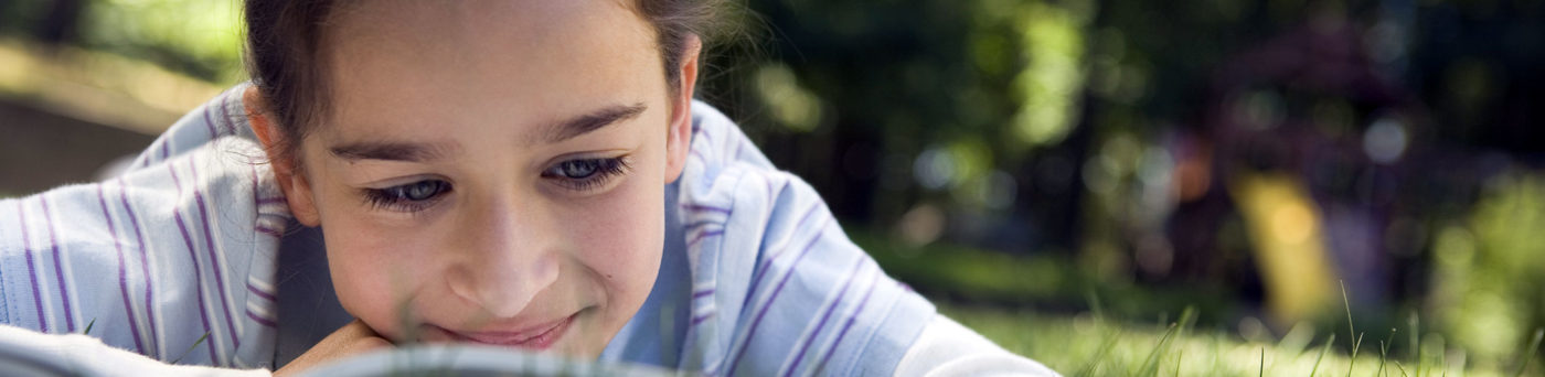 Girl reading in the grass on a sunny day