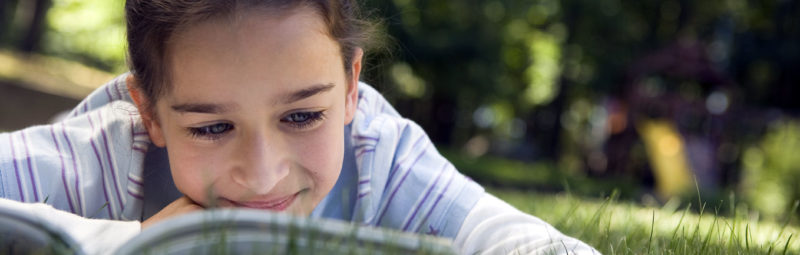 Girl reading in the grass on a sunny day