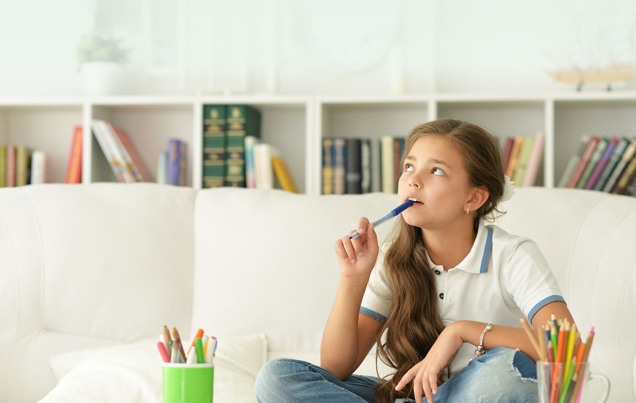 Girl thinking about her homework assignments with a pen at her mouth.