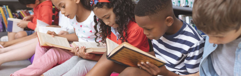 A group of students reading non-fiction books together in the library