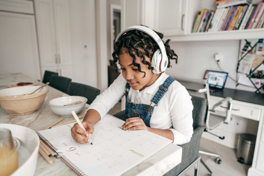 A girl shows her good homework habits by filling out her calendar.