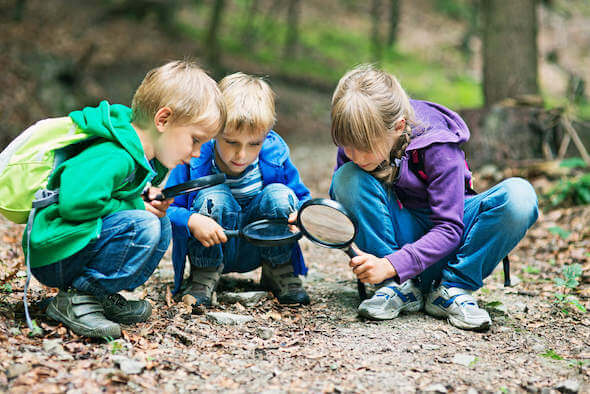 Children exploring outdoors with magnifying glass