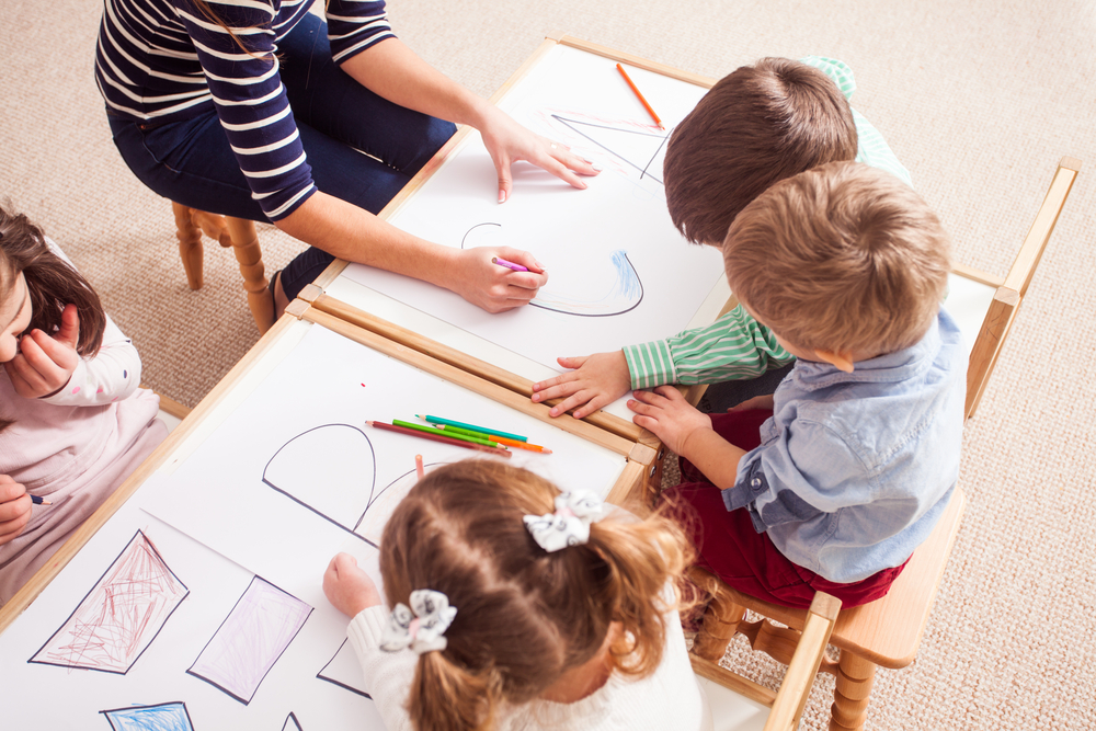 Children practice drawing and coloring in letters.