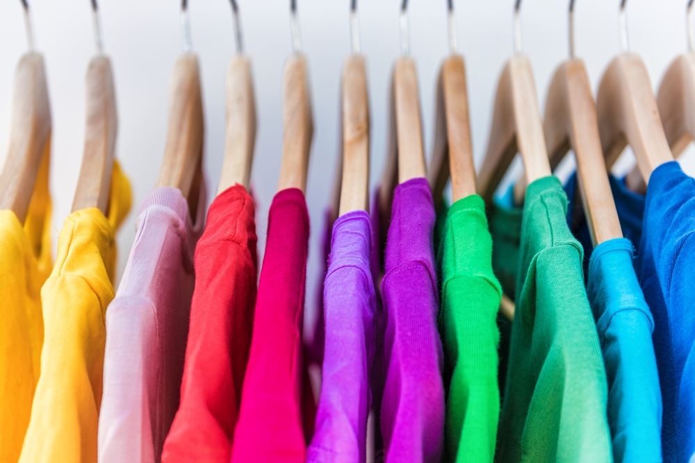 Colorful shirts hang in a closet.