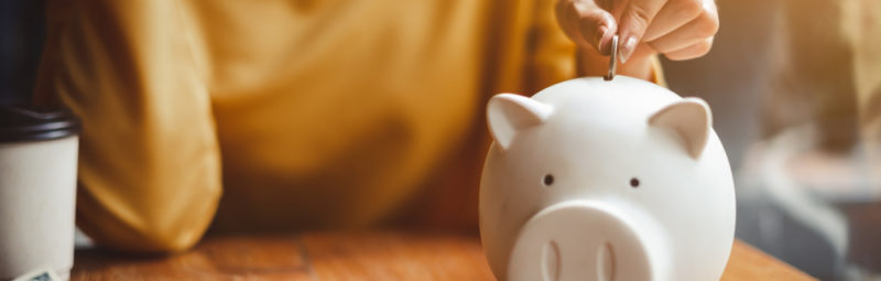 A woman saves coins in a piggy bank.
