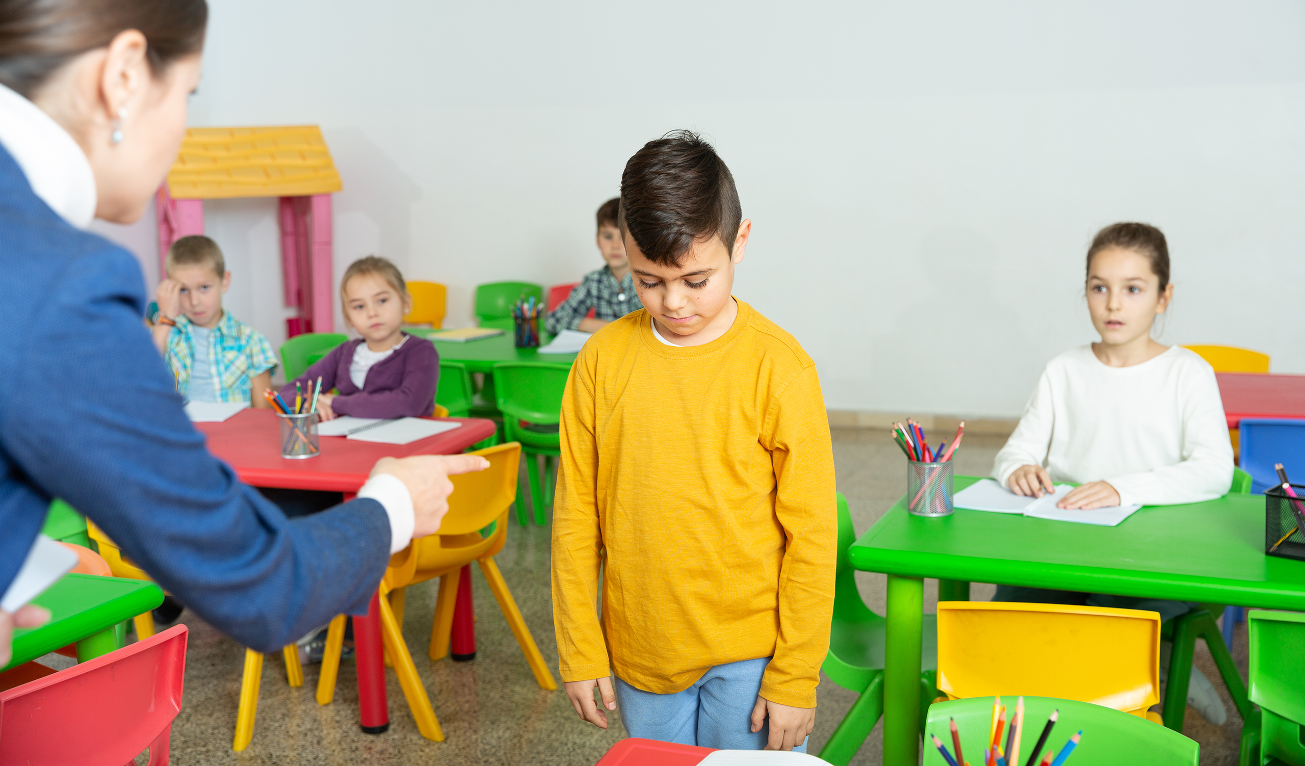 Female elementary school teacher scolding a male student.