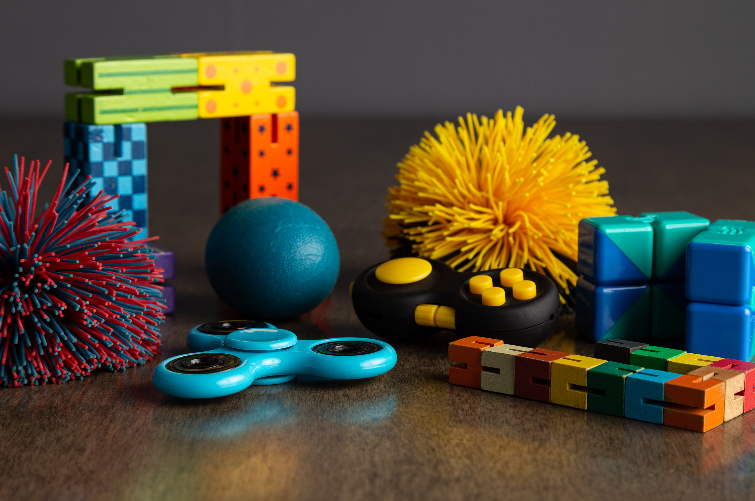 Colorful fidget toys including spinner, stress ball, clicker, and puzzles.