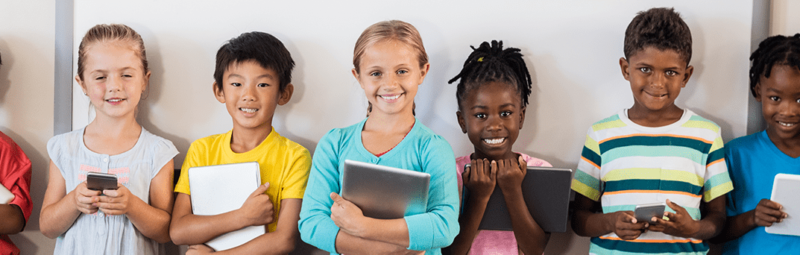 Group of seven boys and girls holding various electronic devices.