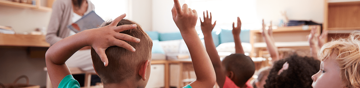 Students raise their hands to participate during an interactive read aloud.