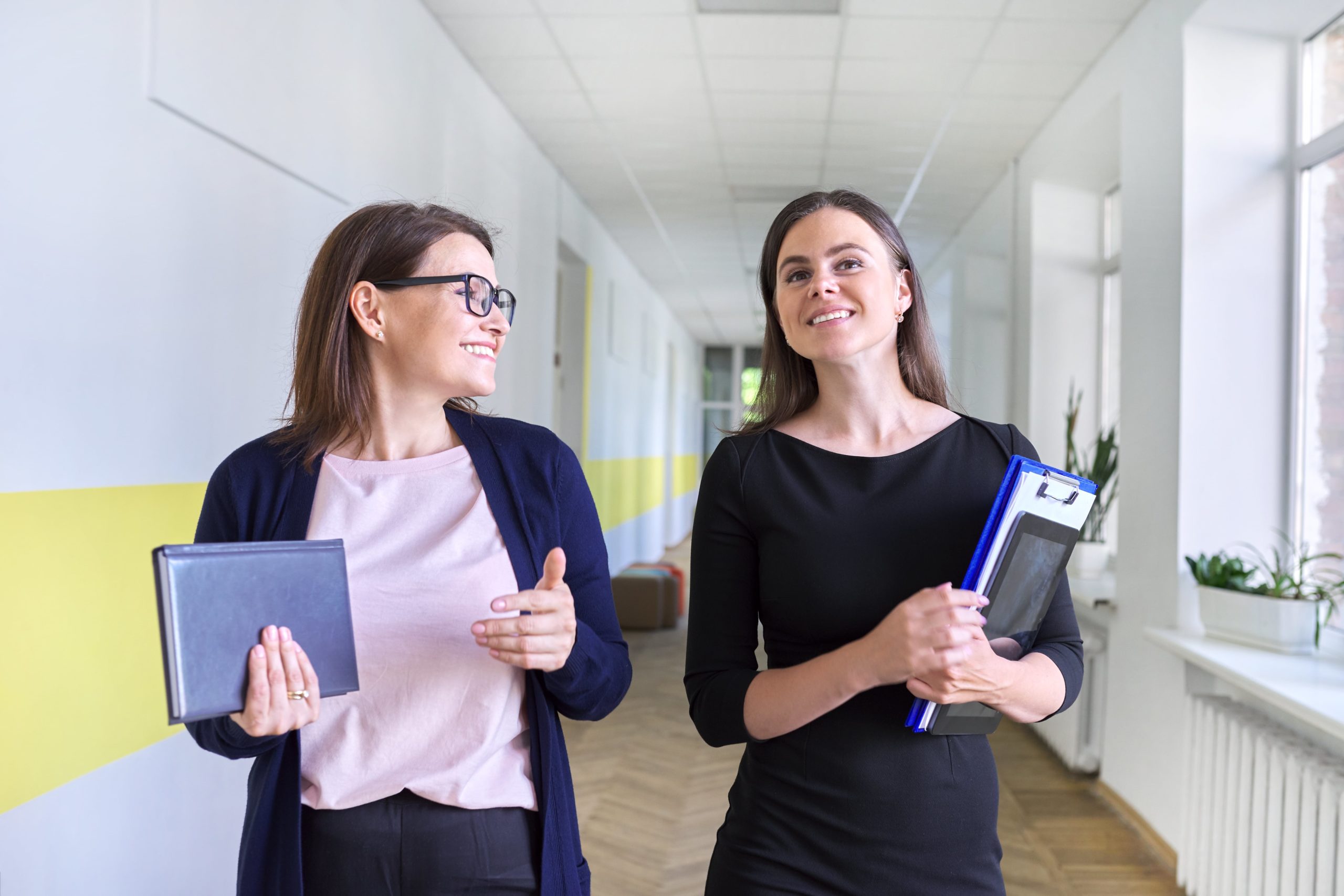 Two female teachers walking down a school hallway.