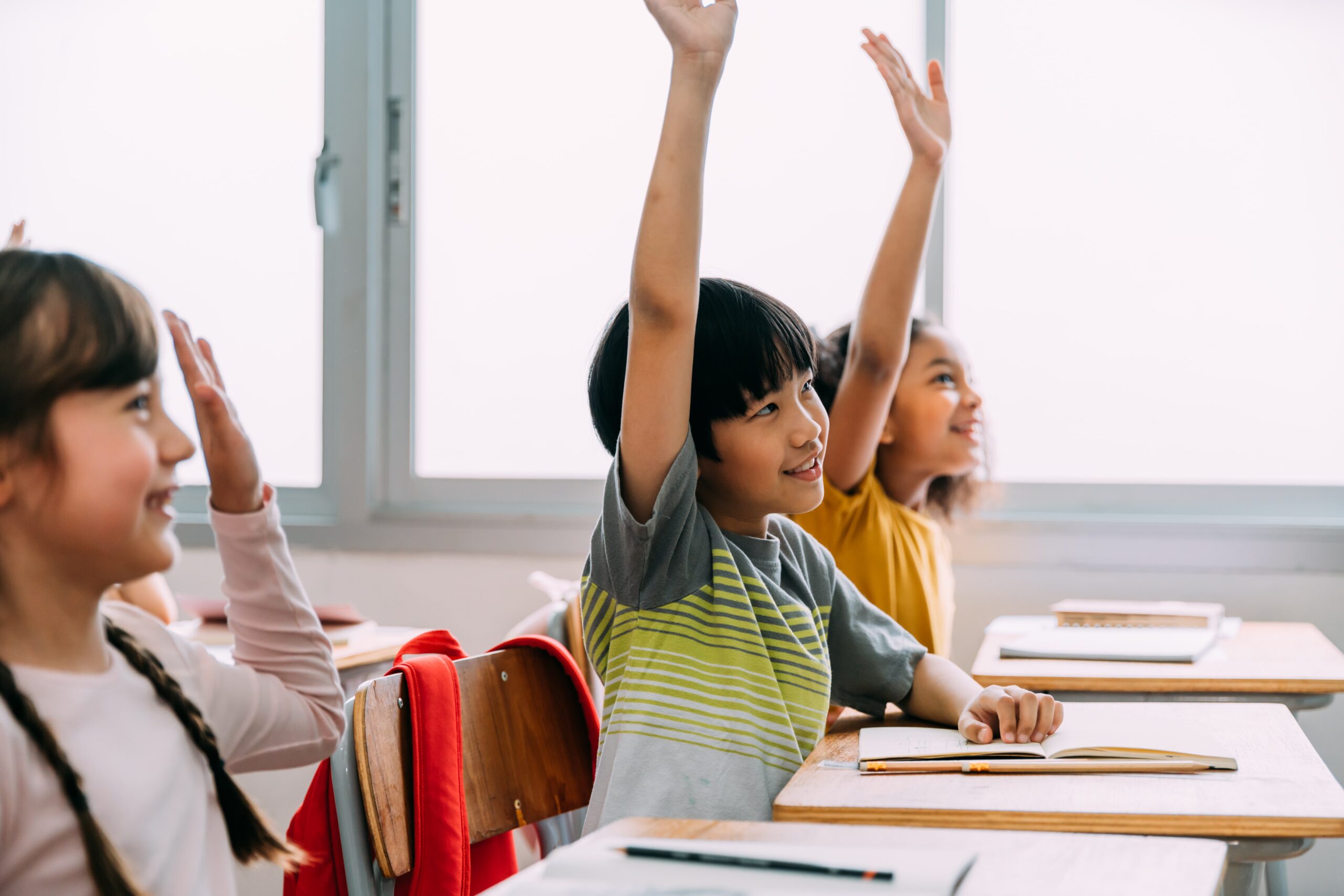 Students raising their hands to answer a question in class.