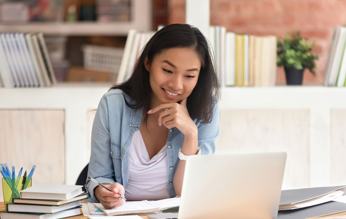 A smiling teacher working at her laptop.