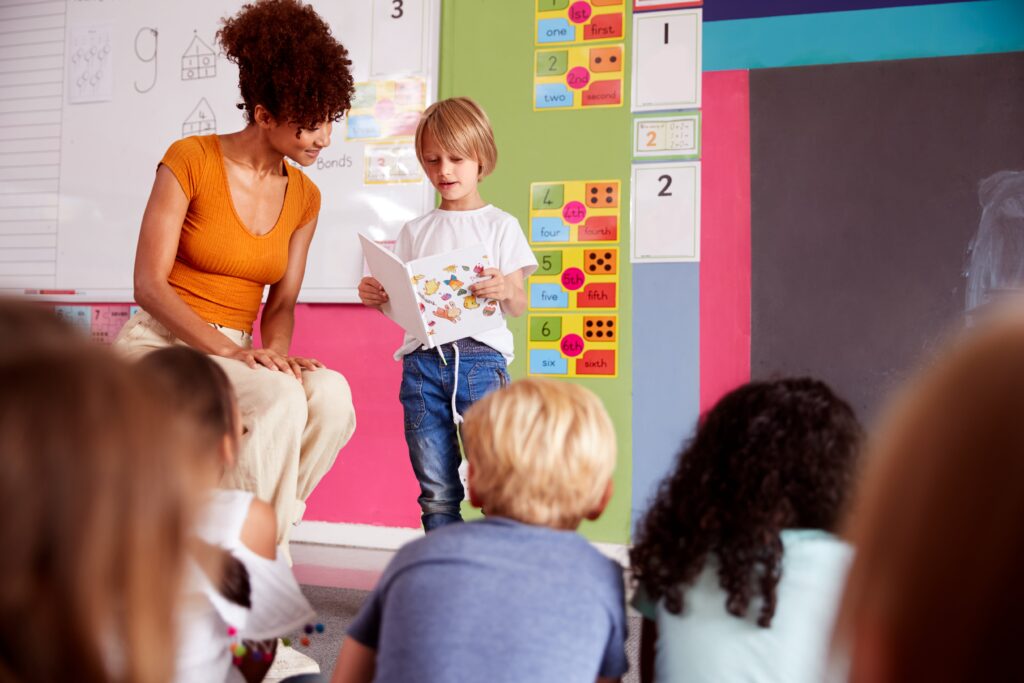 Elementary student reading in front of classmates.