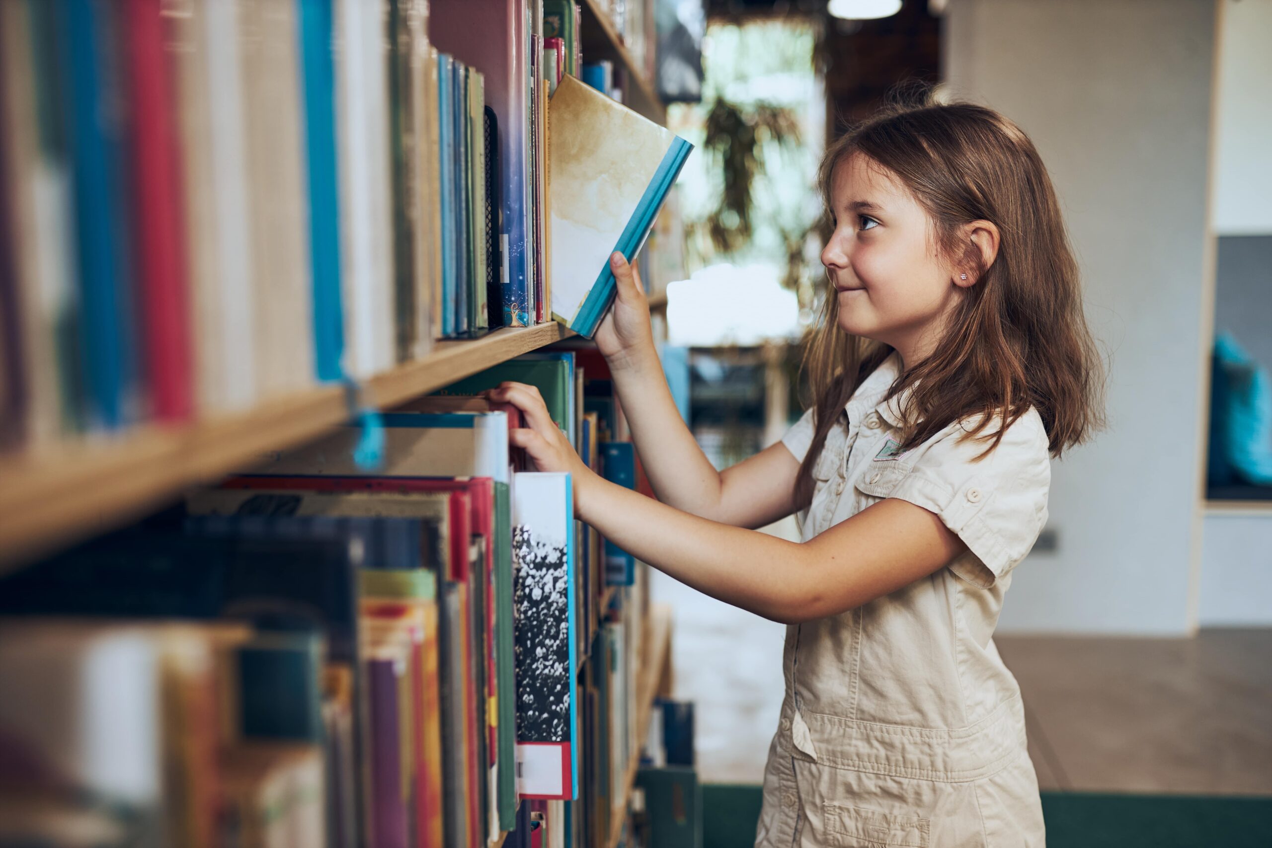 Young girl picking books out in a library.
