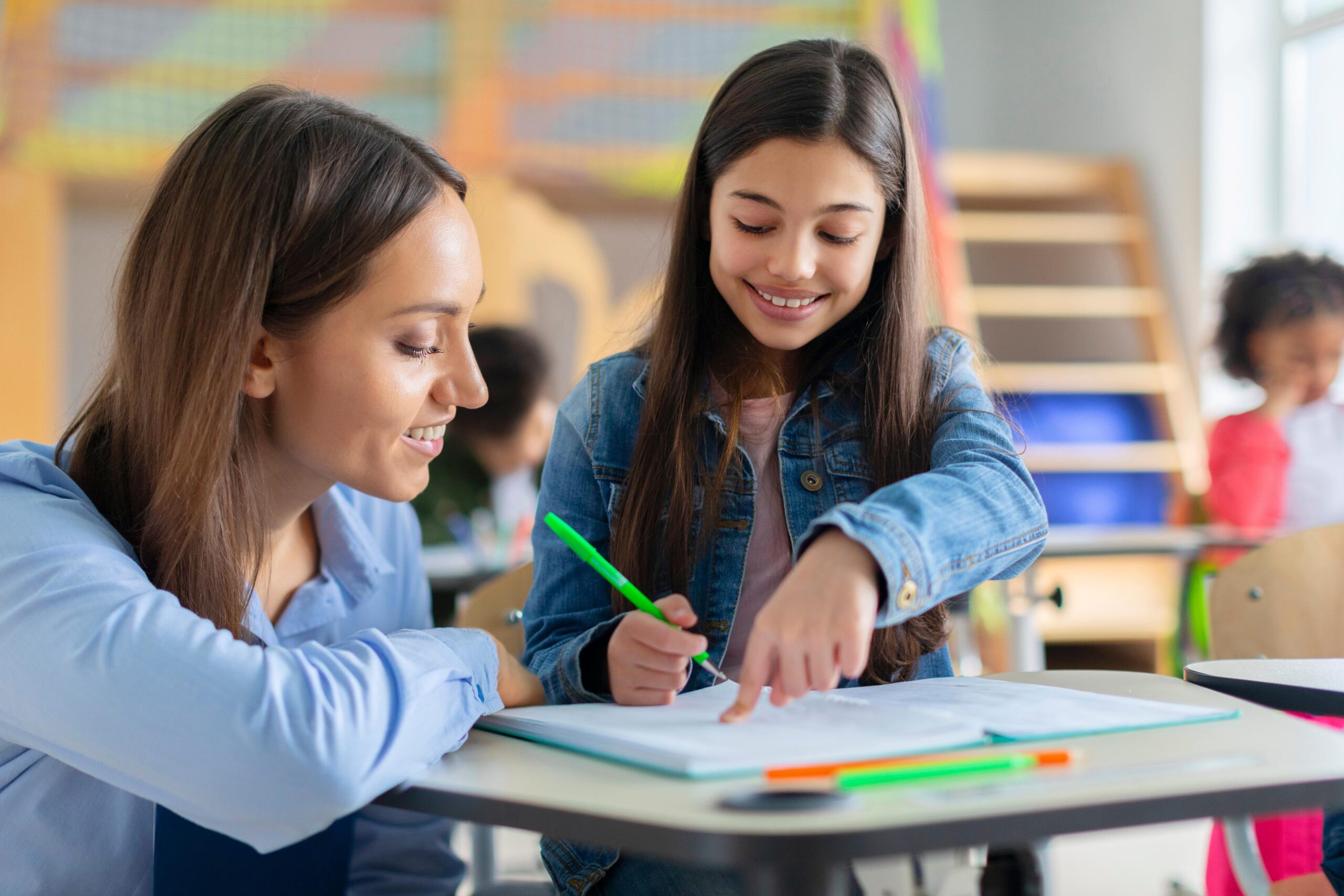 Teacher helping student at her desk.