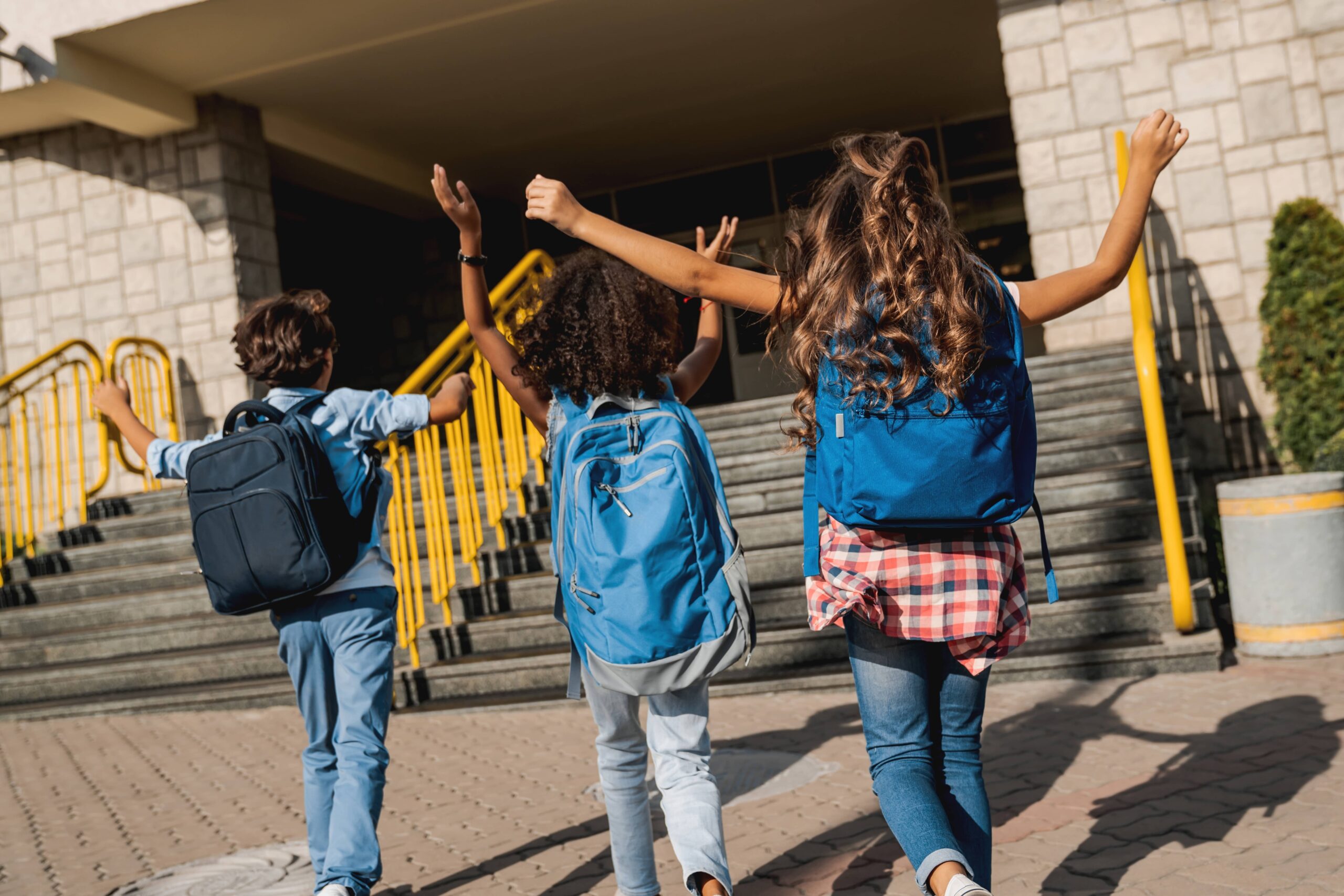 Students walking into school with their arms in the air to celebrate the 100th day of school.