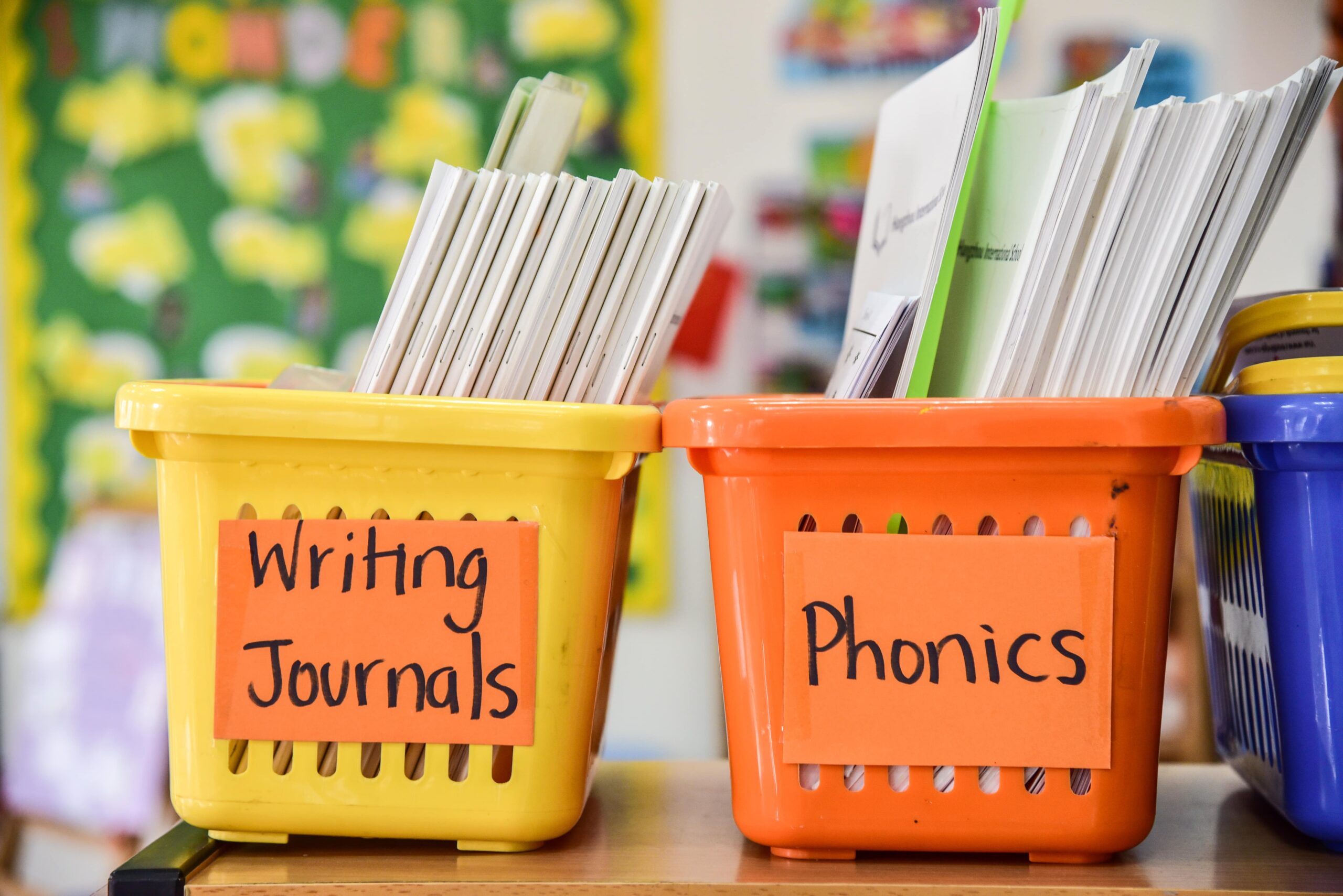 Organized bins for classroom writing supplies and notebooks.