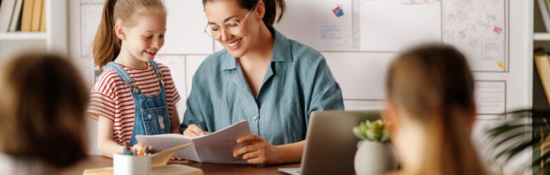 Teacher helping a student at their desk.