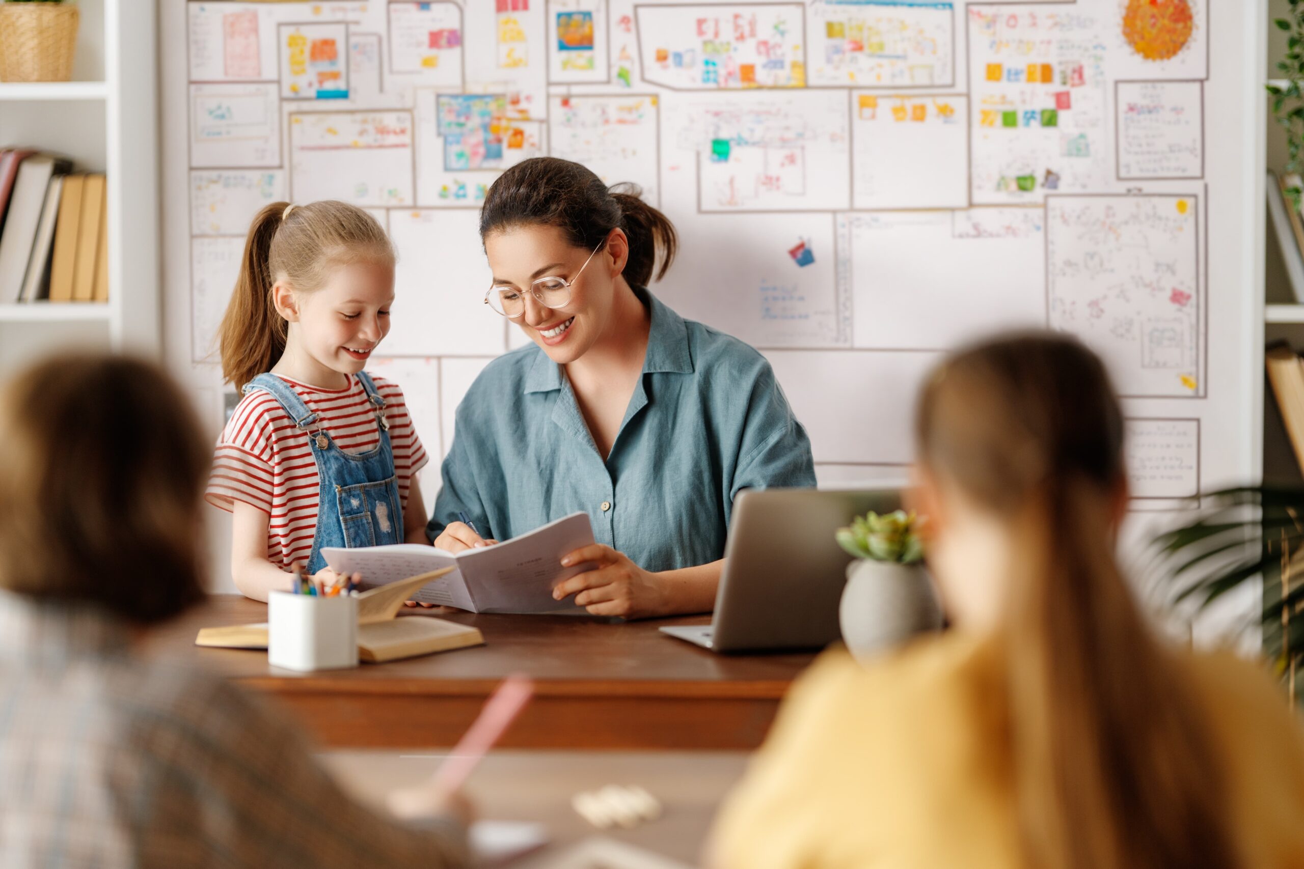 Teacher helping a student at their desk.