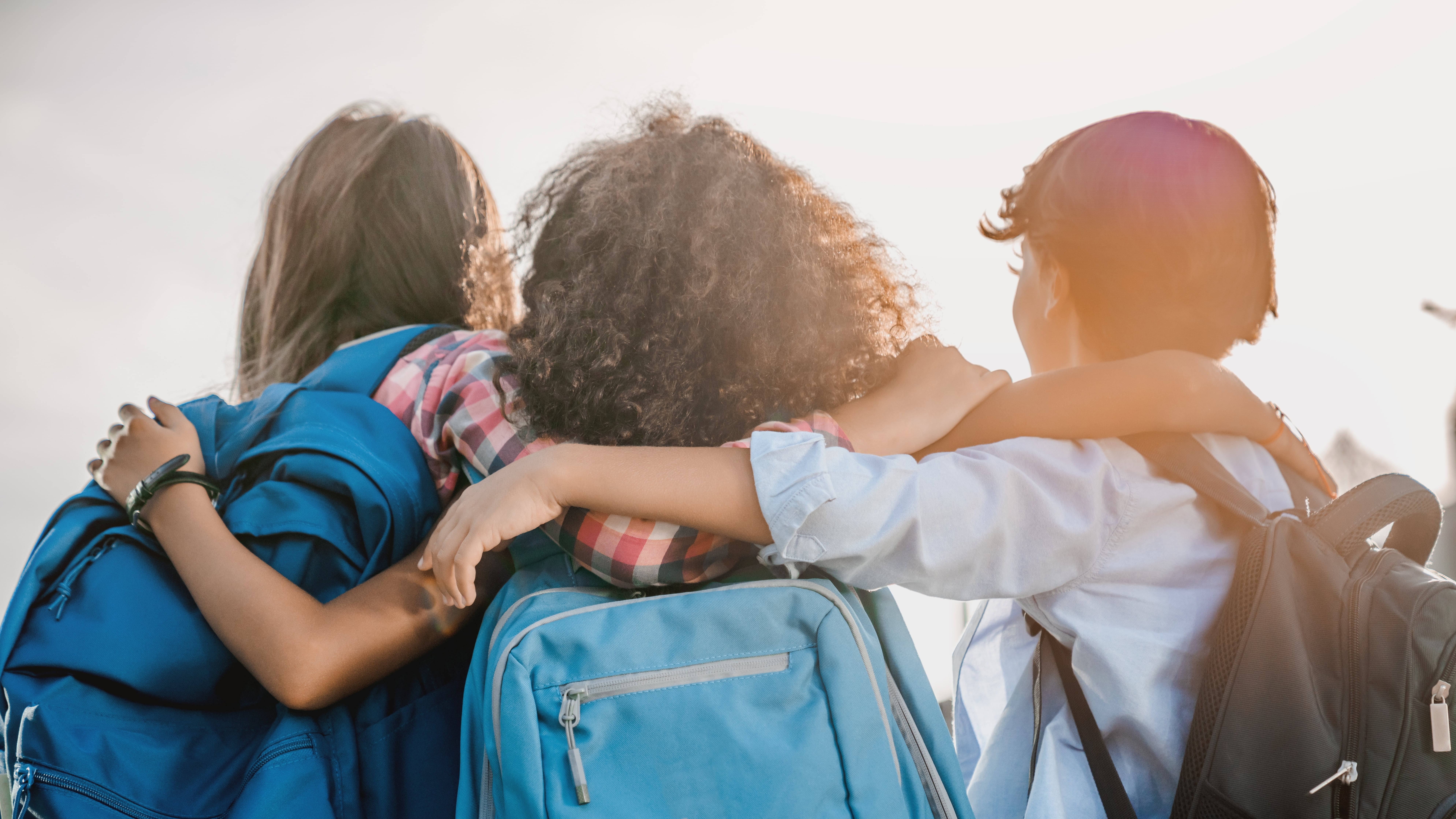 Group of students with their backs to the camera with their arms around each other.