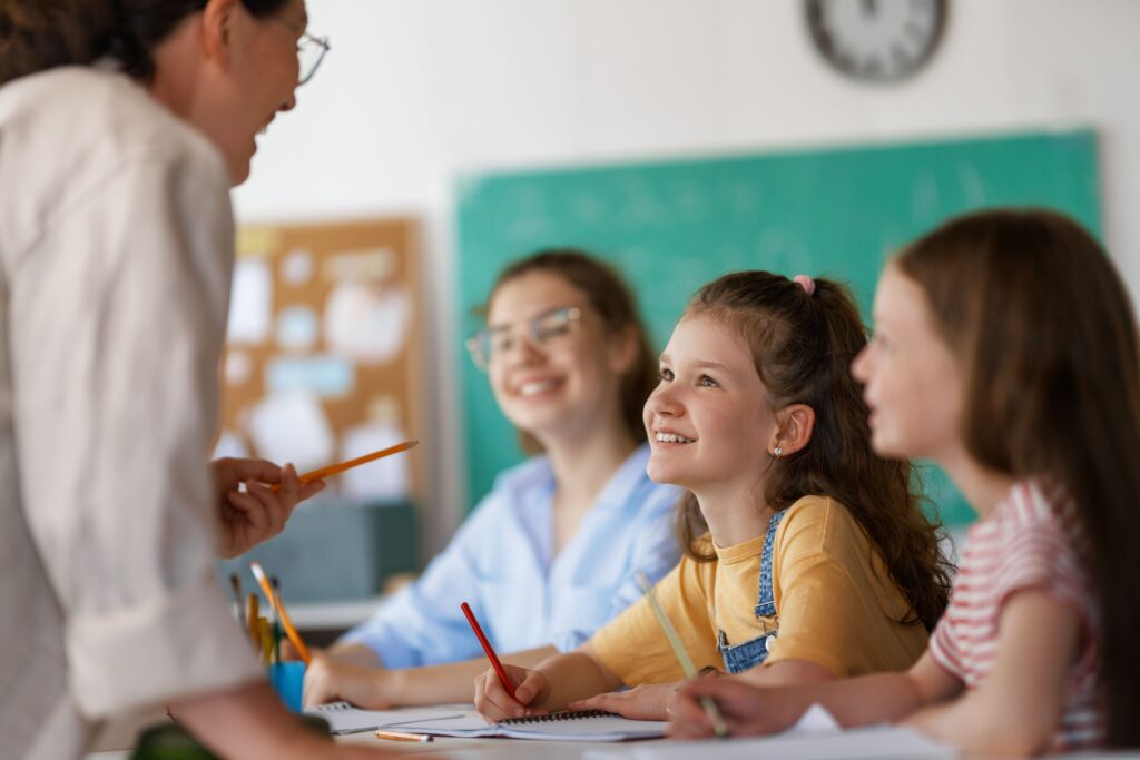 Elementary students speaking to their teacher in class.