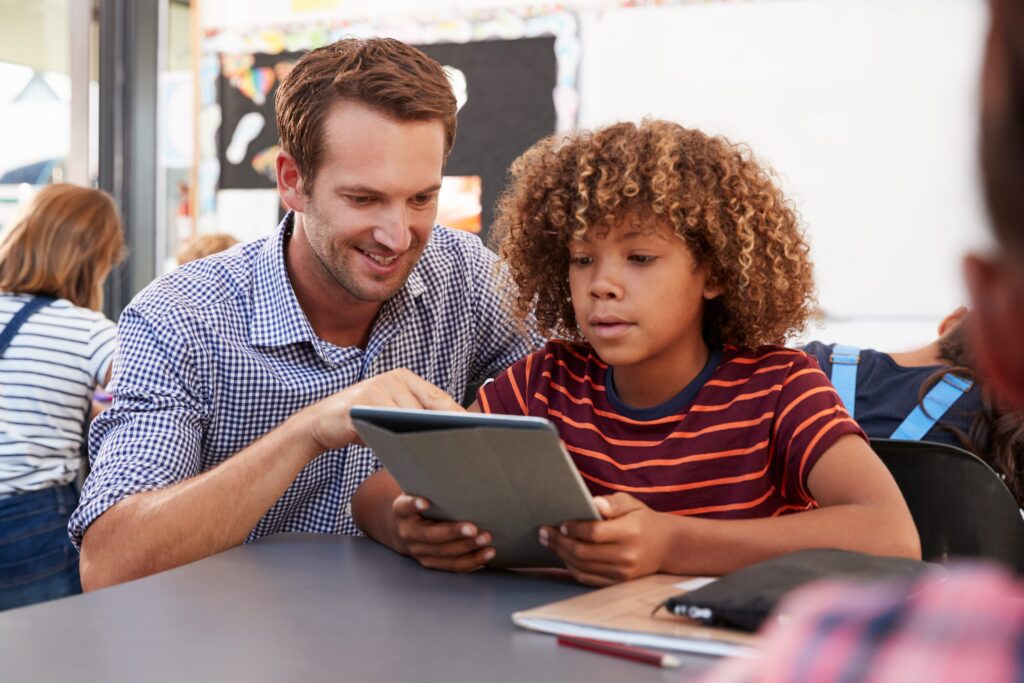 A teacher assisting a student on an iPad.