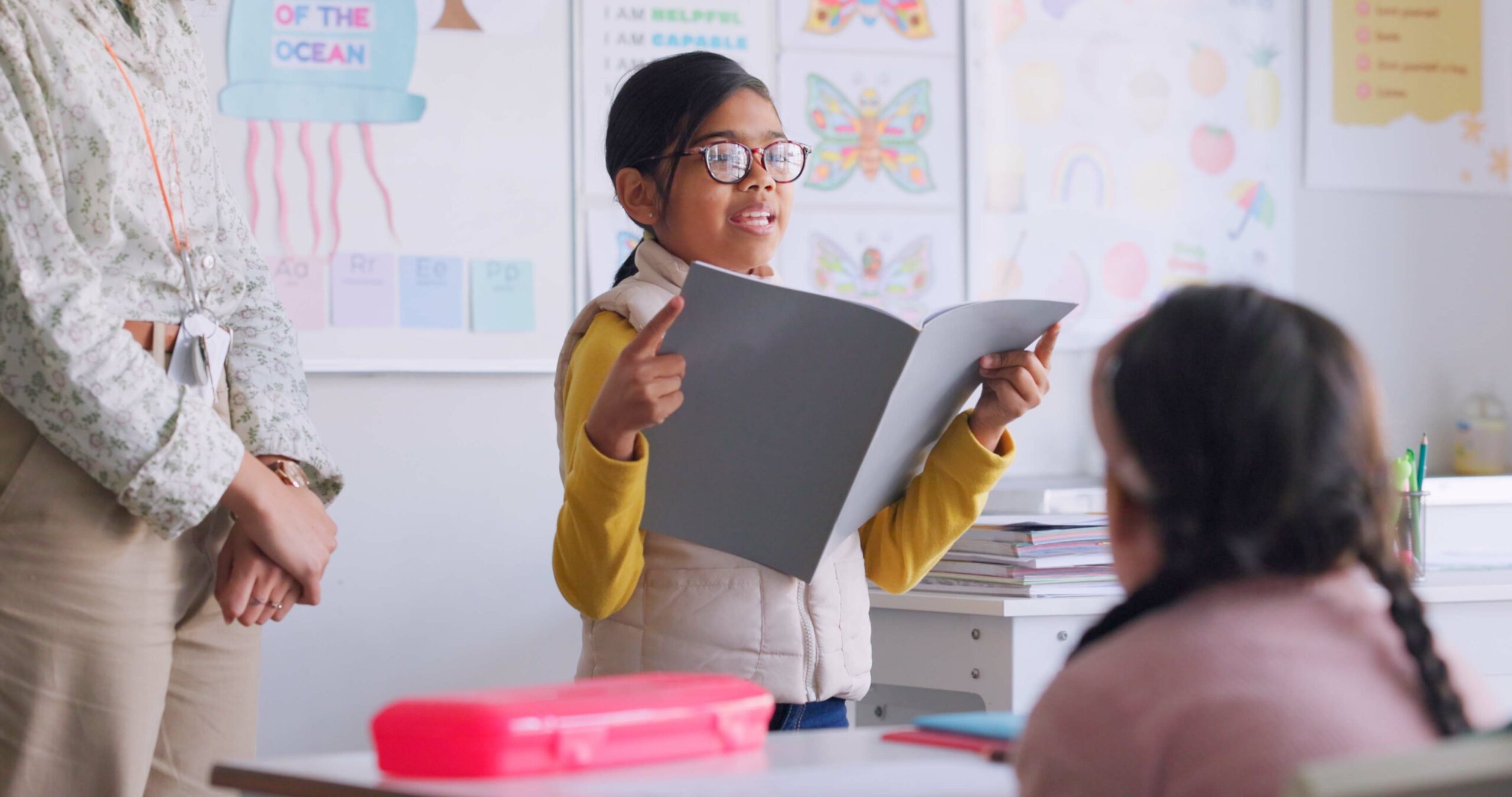 Elementary student reading in front of her class.