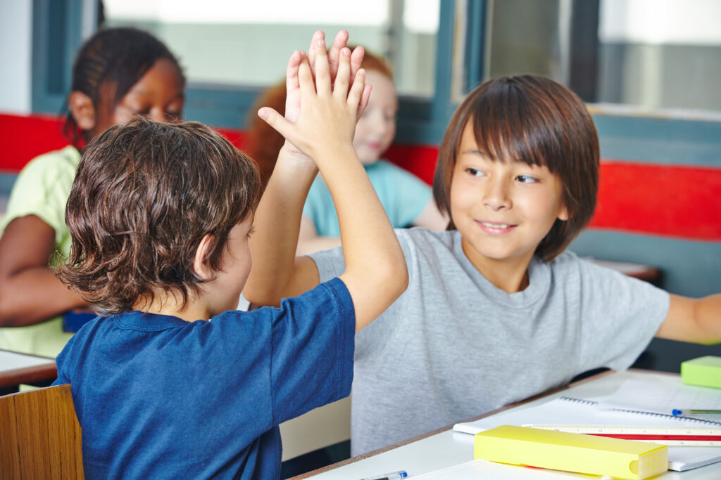 two elementary students greeting each other witha high five