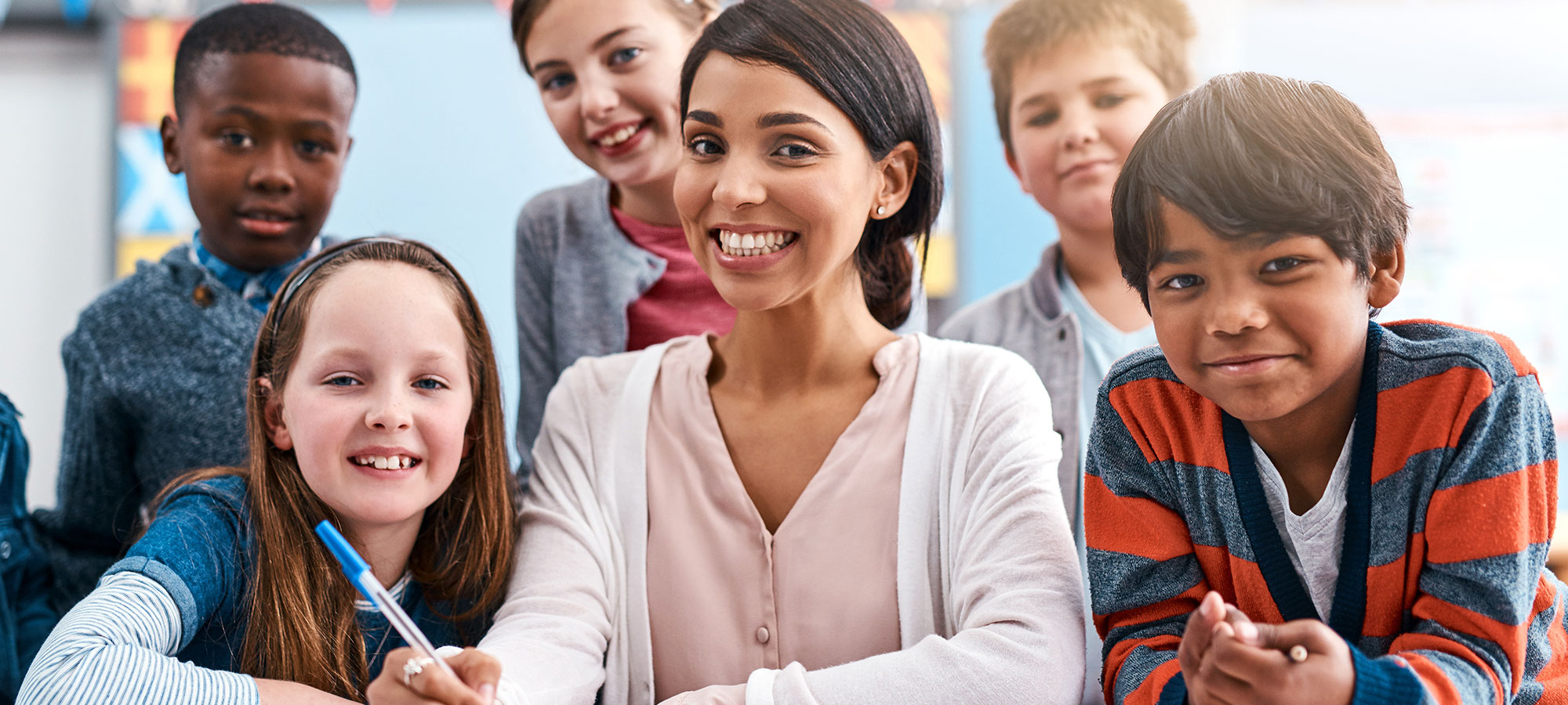 A happy teacher and group of children in the classroom