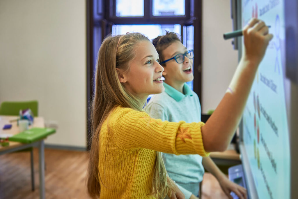 Two students take a break by drawing on a digital whiteboard